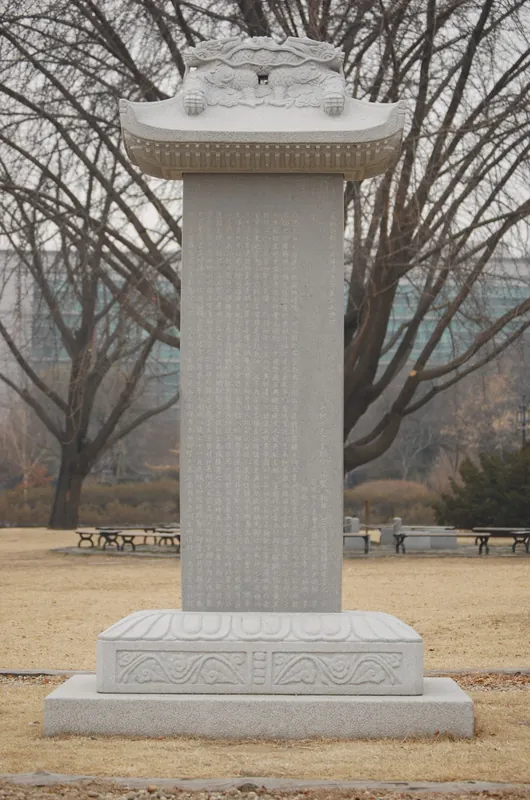 겨울 숲을 배경으로 서 있는 지붕돌을 얹은 돌비석