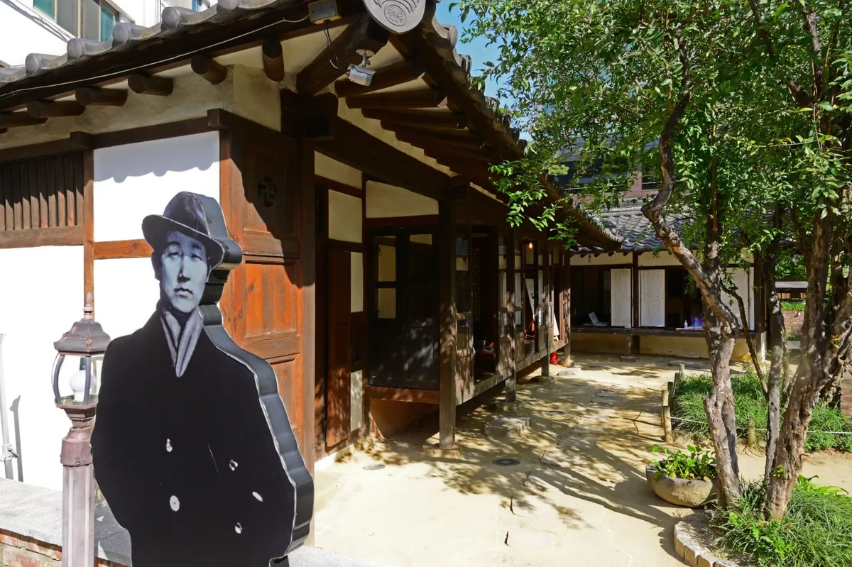 한옥 마당에 시인의 실물 크기 사진 입간판이 서 있다