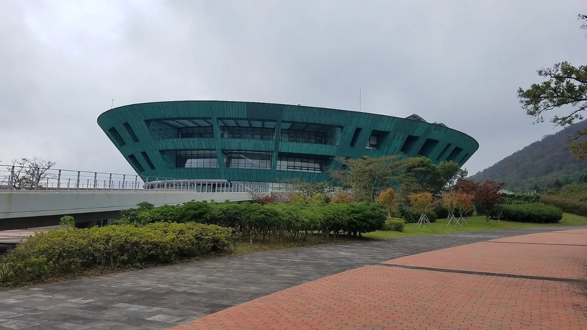 잔디밭과 붉은 길 너머로 푸른 지붕의 원형 건물이 보이는 풍경