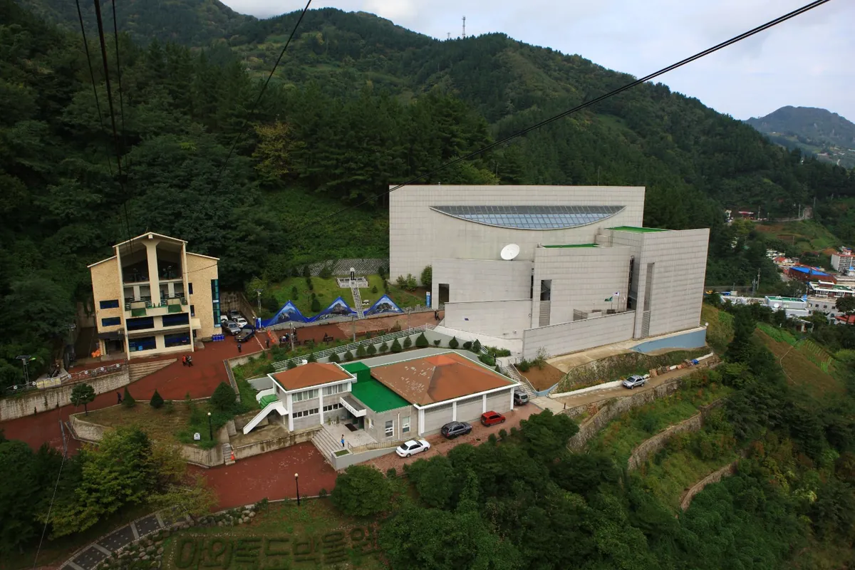 울릉도 산자락 숲속에 들어선 흰색 독도박물관 건물을 위에서 내려다본 모습.