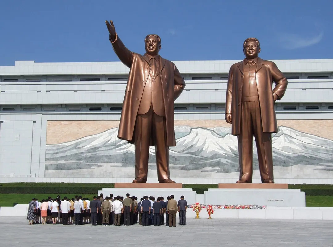 건물 앞에 선 거대한 청동 입상 두 개와 그 앞의 참배객들