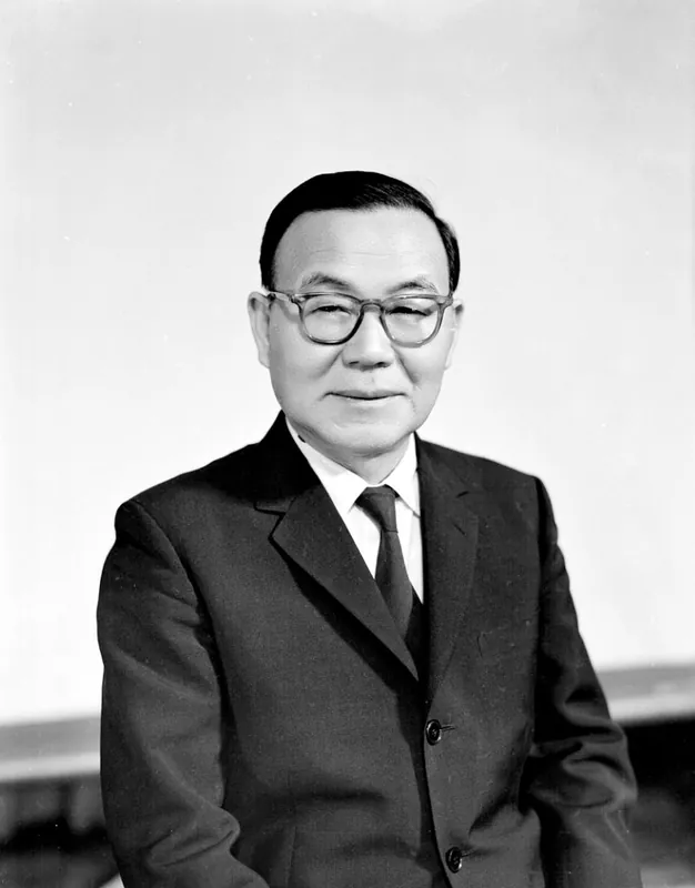 안경을 쓴 양복 차림 남성의 흑백 인물 사진