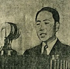 마이크 앞에서 연설하는 양복 차림 남성의 흑백 사진